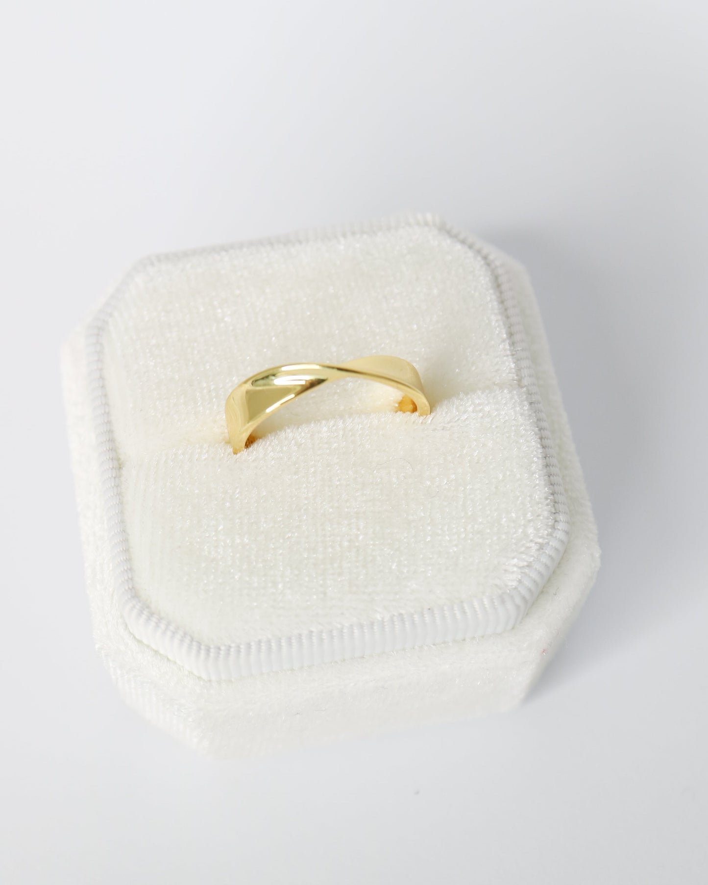 Gold ring on a white cushion with a white background
