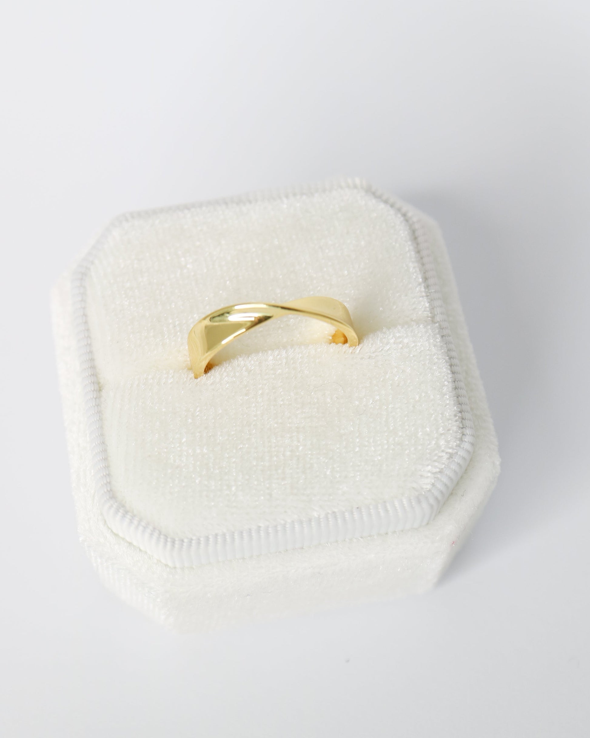 Gold ring on a white cushion with a white background