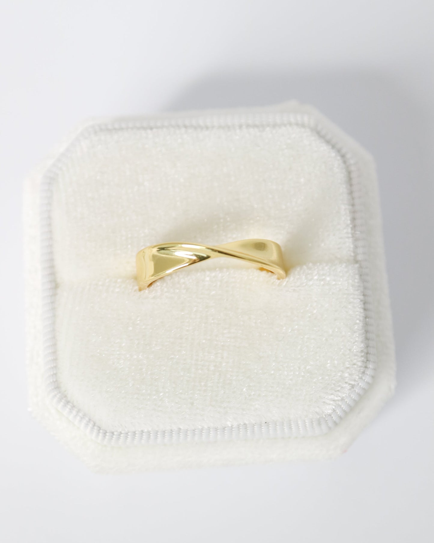 Gold ring on a white cushion with a white background