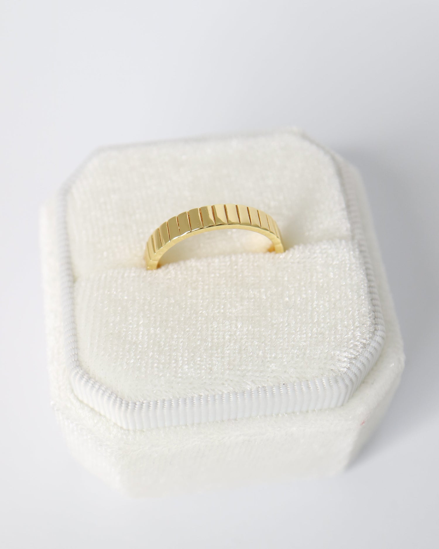 Gold ring on a white cushion with a white background