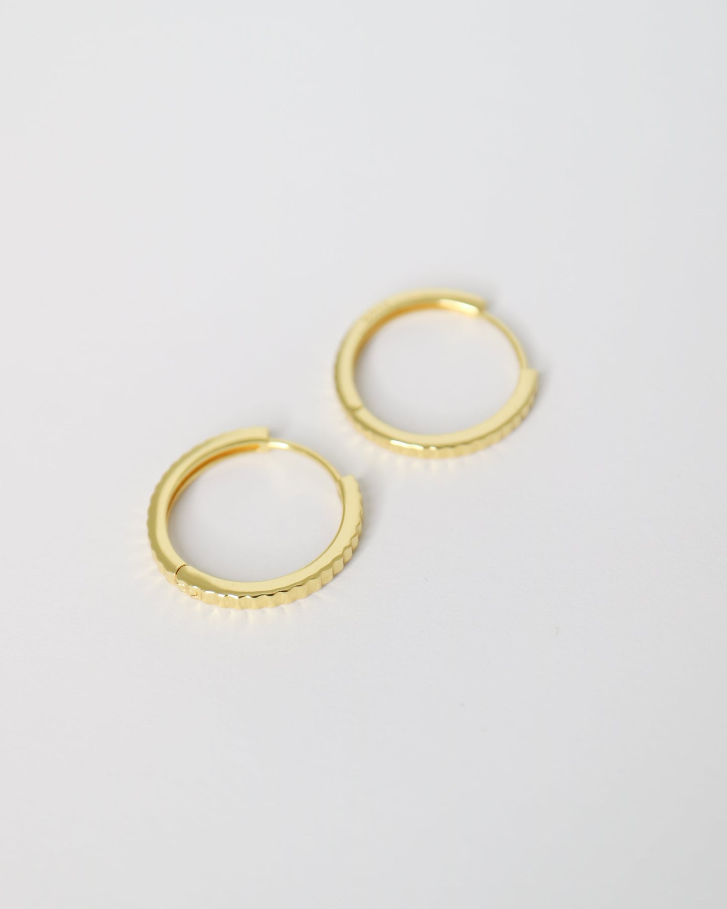 Pair of gold hoop earrings on a light gray background