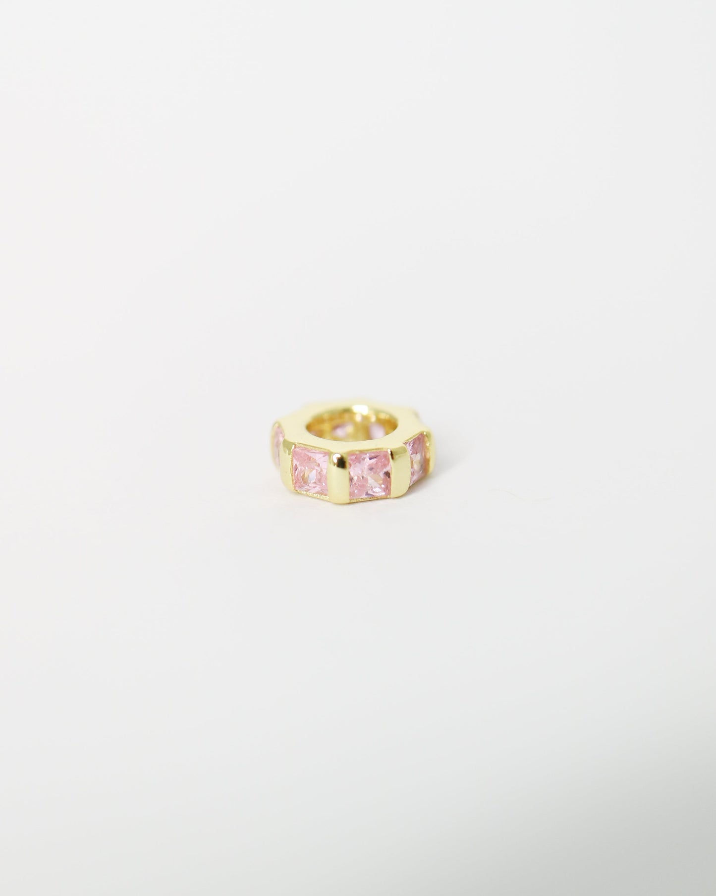 Gold ring with a pink gemstone on a light gray background