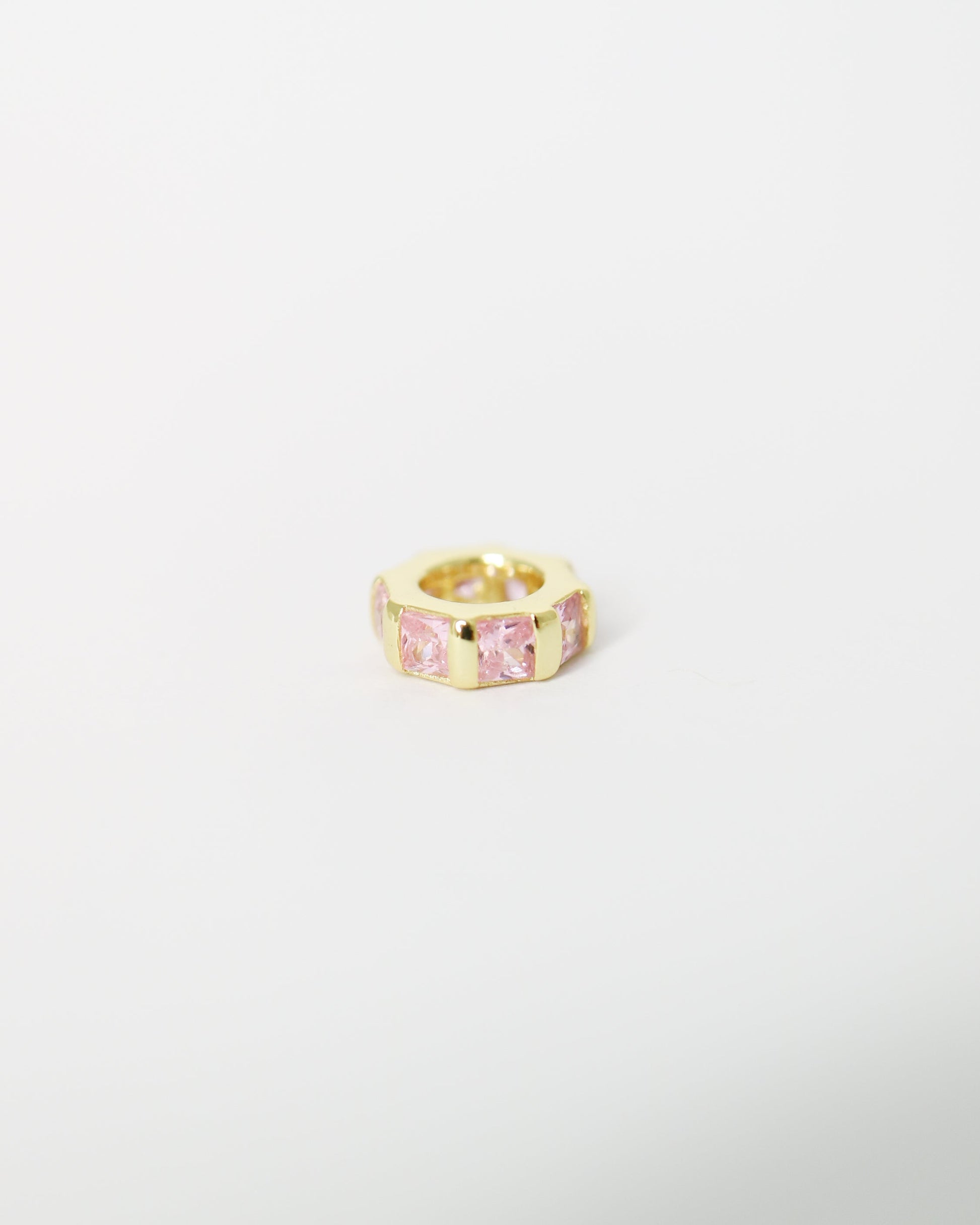 Gold ring with a pink gemstone on a light gray background