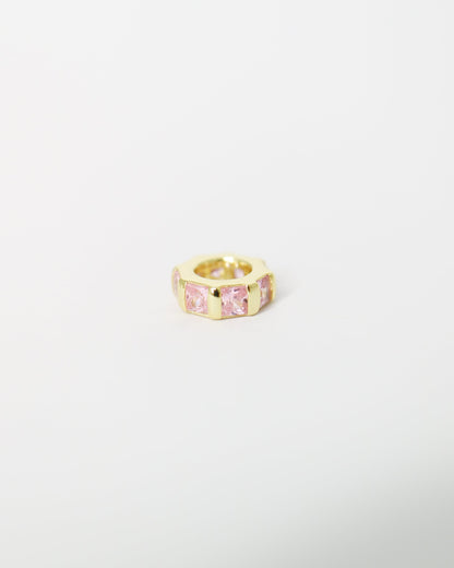 Gold ring with a pink gemstone on a light gray background