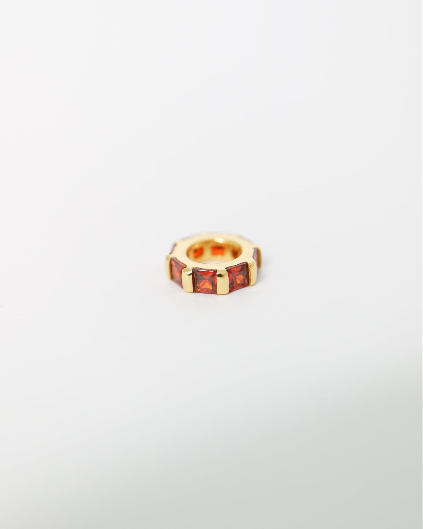 Small gold ring with embedded stones on a light gray background