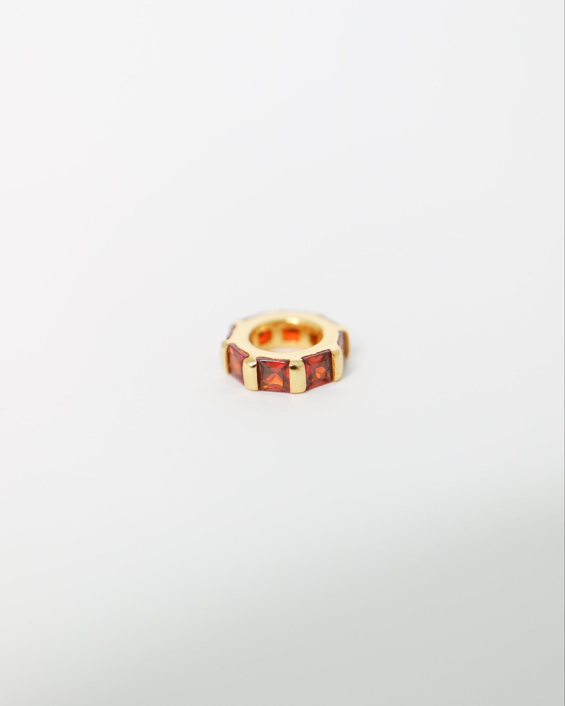Small gold ring with embedded stones on a light gray background