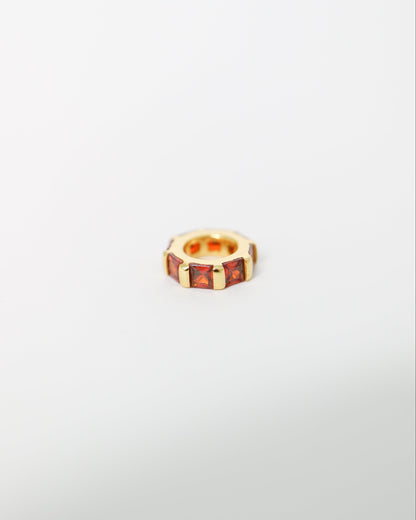 Small gold ring with embedded stones on a light gray background