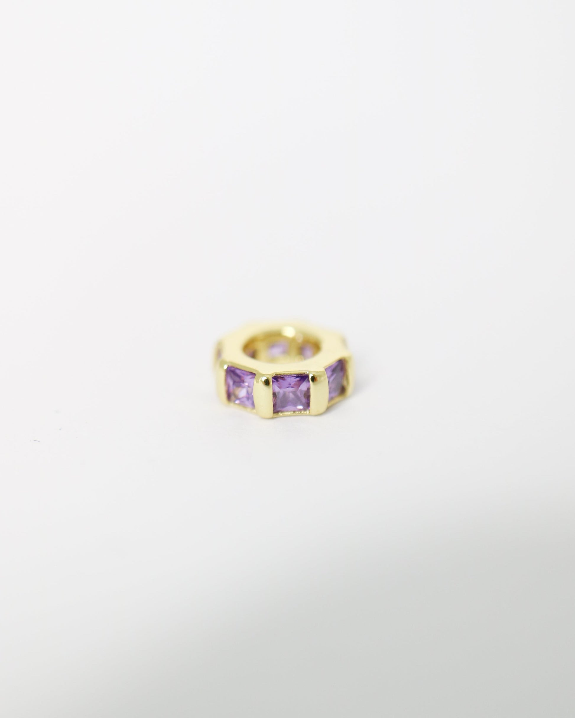Gold ring with purple gemstones on a light gray background