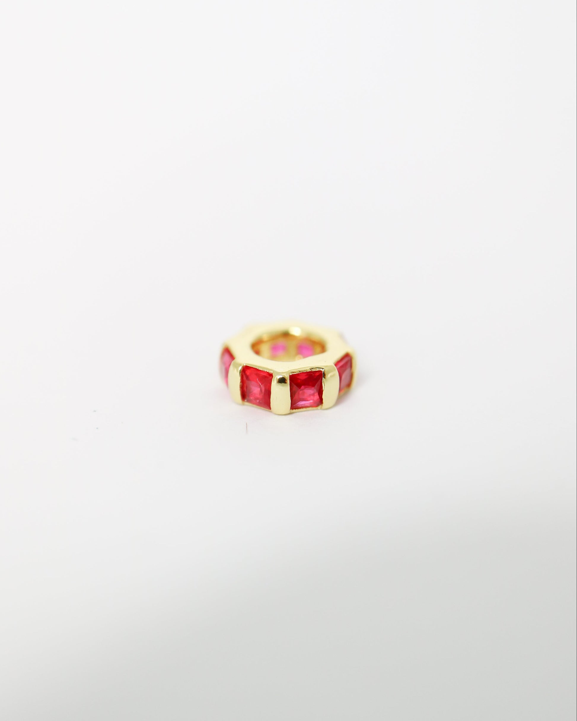 Gold ring with red gemstone on a light gray background