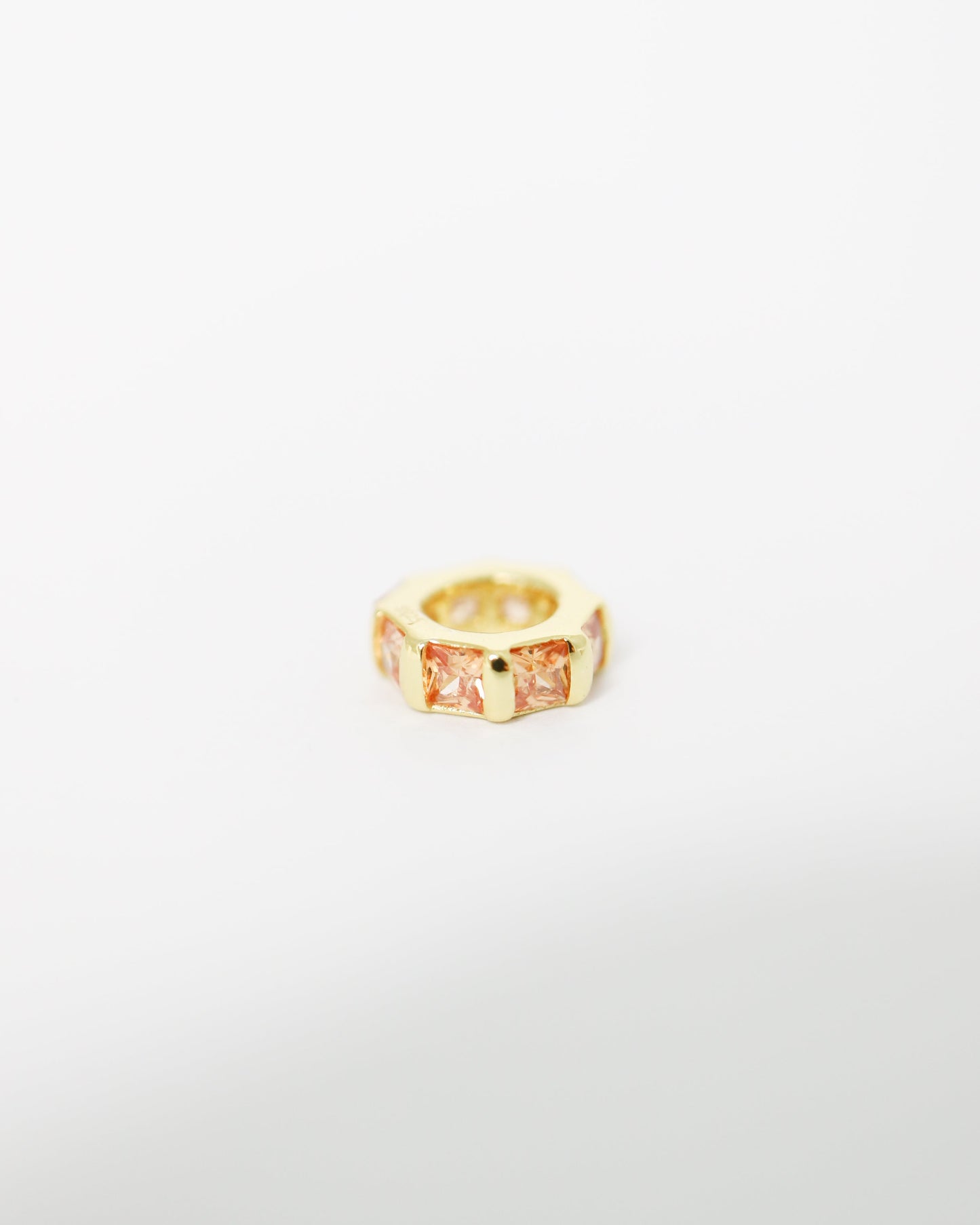 Gold ring with a central gemstone on a white background