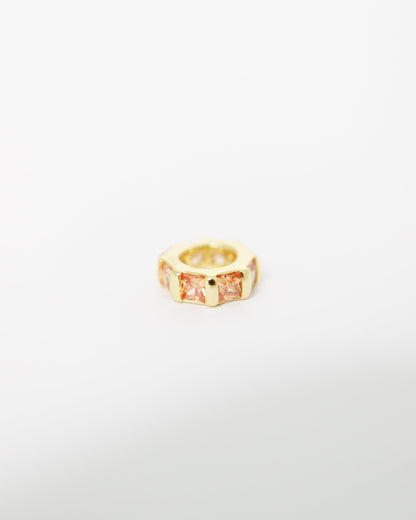 Gold ring with a central gemstone on a white background