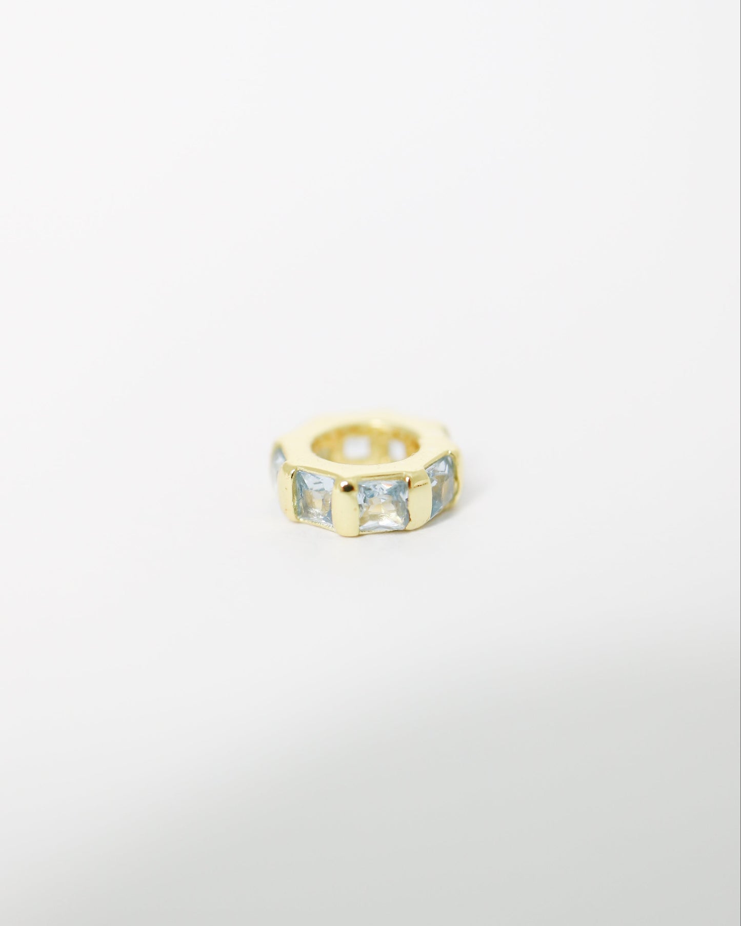 Gold ring with embedded stones on a light gray background