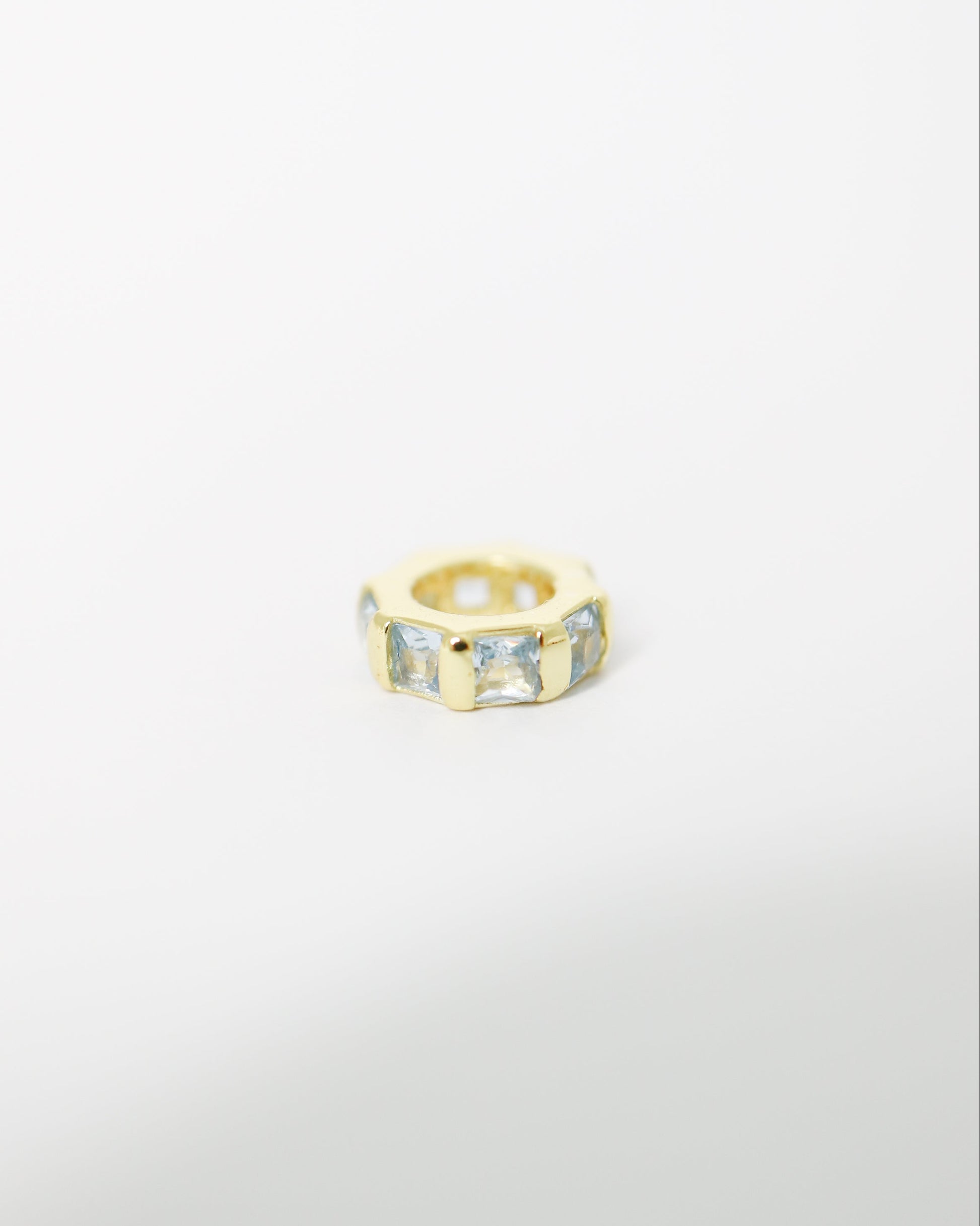Gold ring with embedded stones on a light gray background
