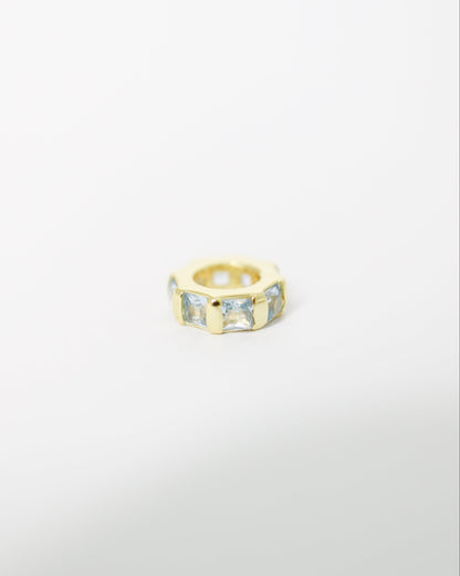 Gold ring with embedded stones on a light gray background