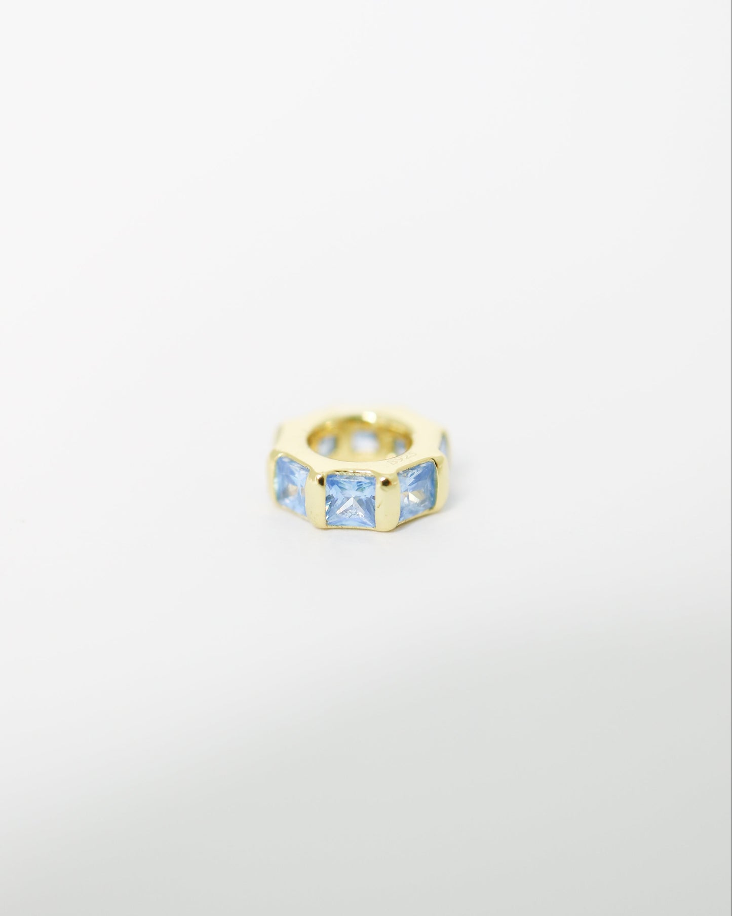 Gold ring with blue gemstones on a light gray background
