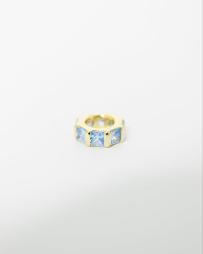 Gold ring with blue gemstones on a light gray background