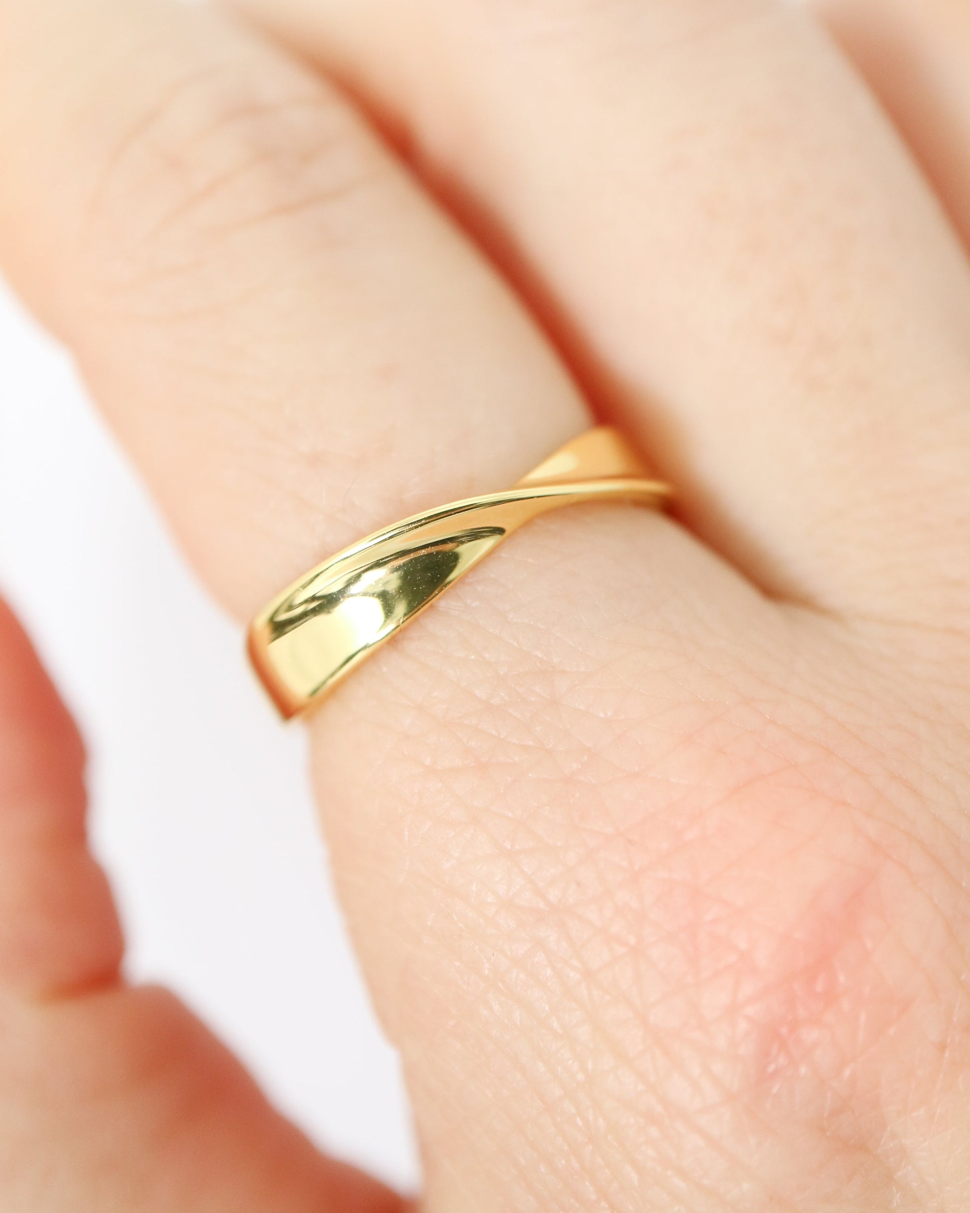 Gold ring on a person's finger against a white background