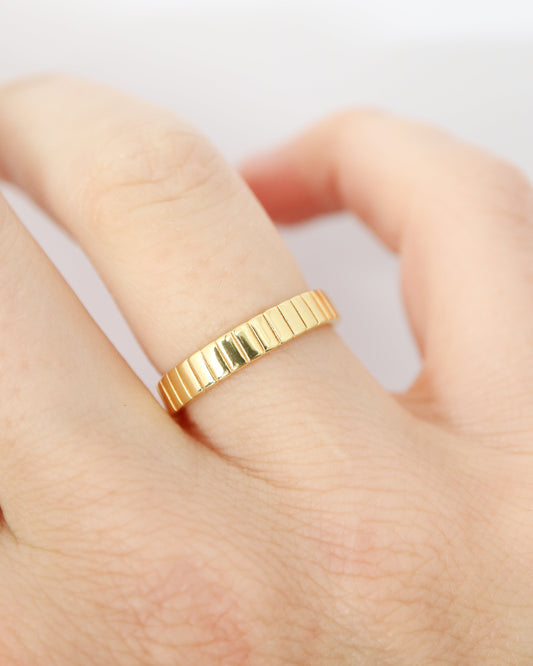 Gold ring on a finger against a light background