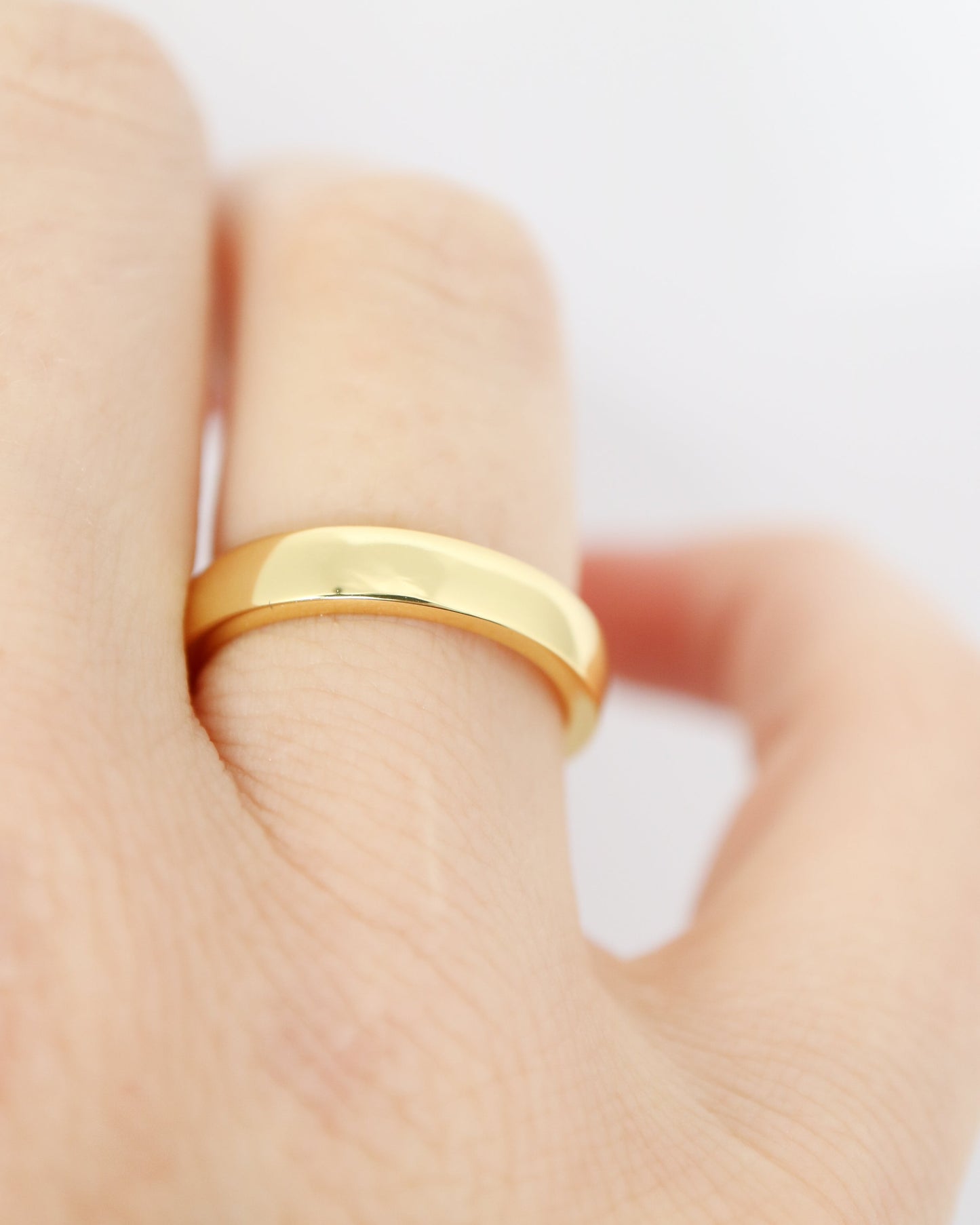 Gold ring on a finger against a white background