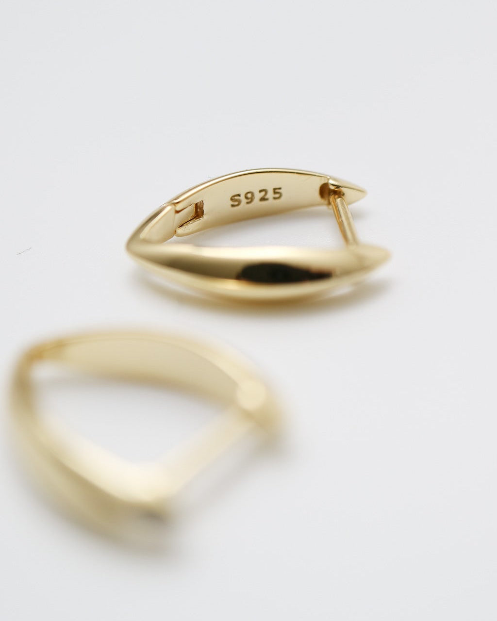 Two gold rings on a light gray background