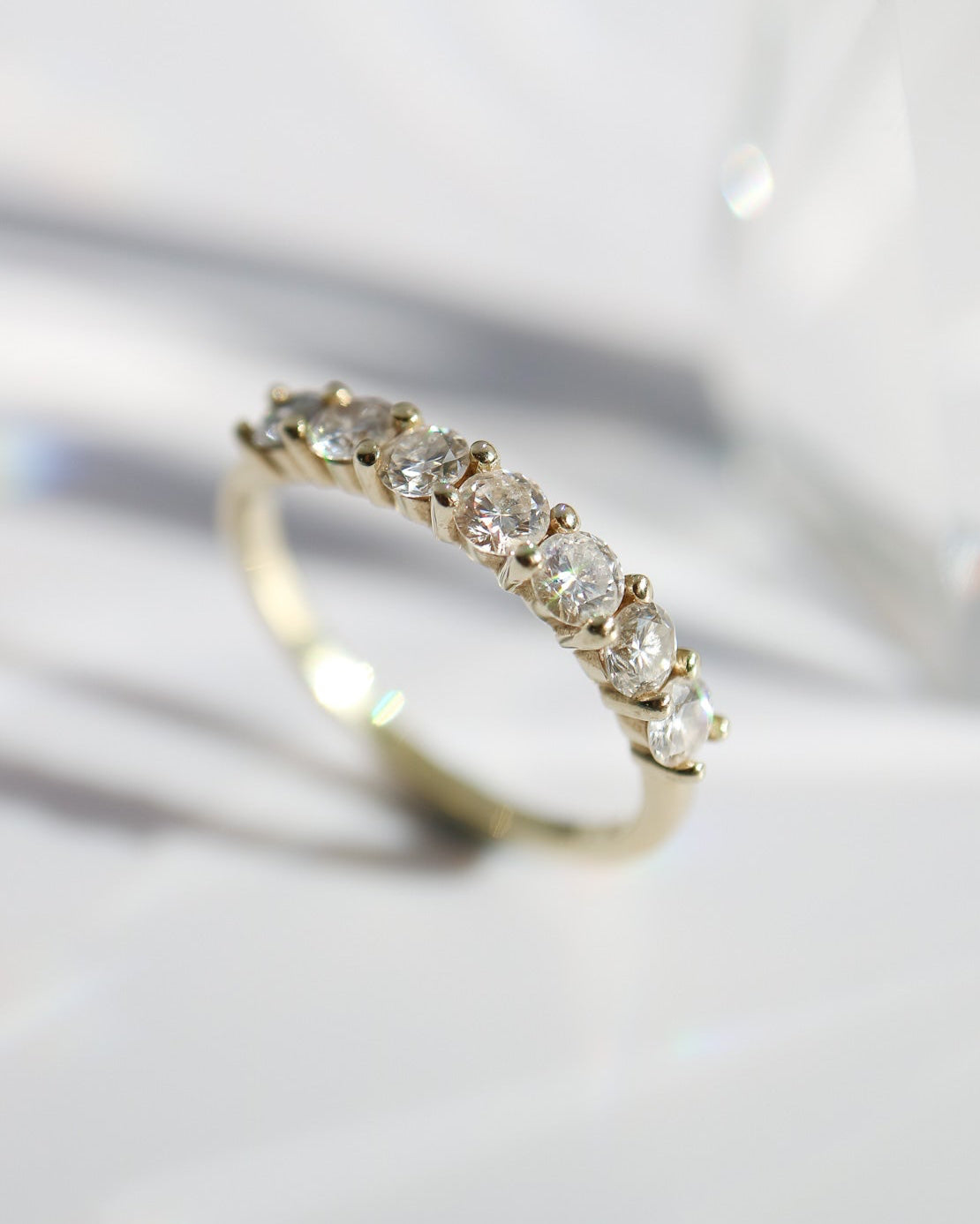 Gold ring with diamonds on a reflective surface