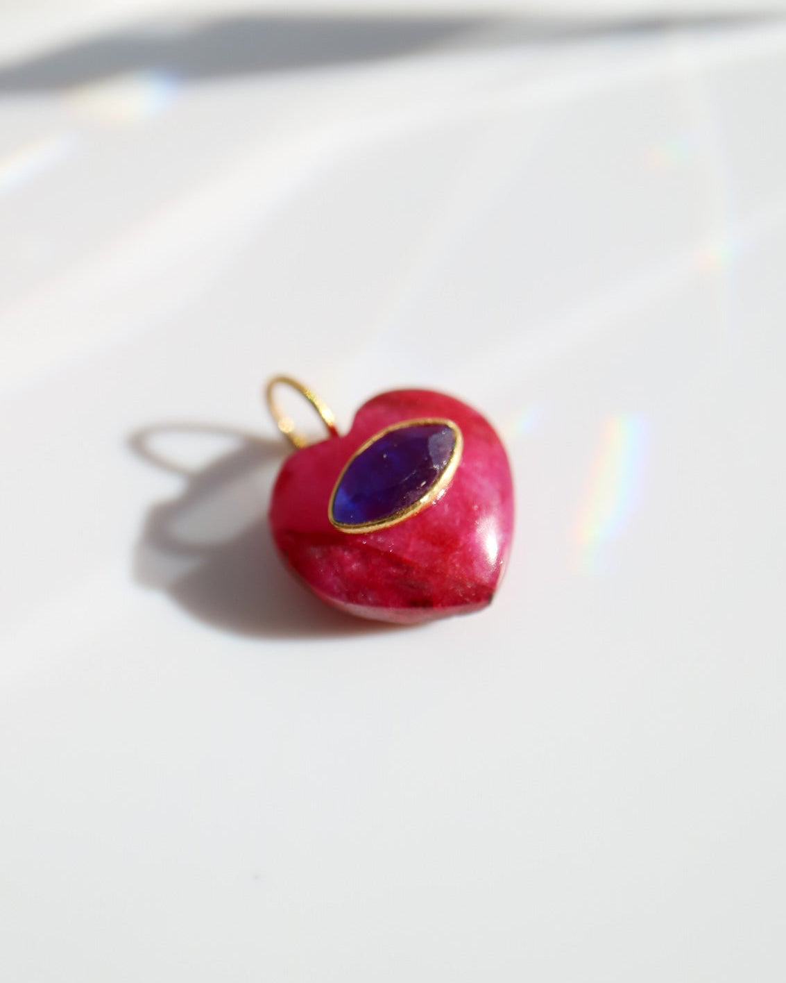 Heart-shaped pendant with a blue gem on a white background