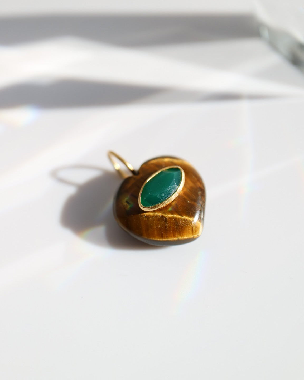 Gold pendant with a green stone on a white background