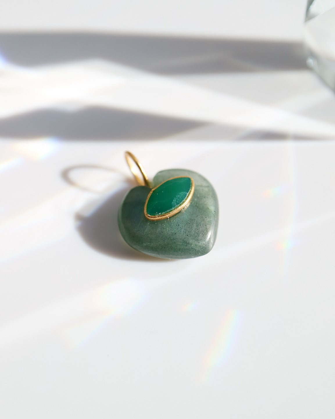 Heart-shaped green pendant with gold frame on a white background