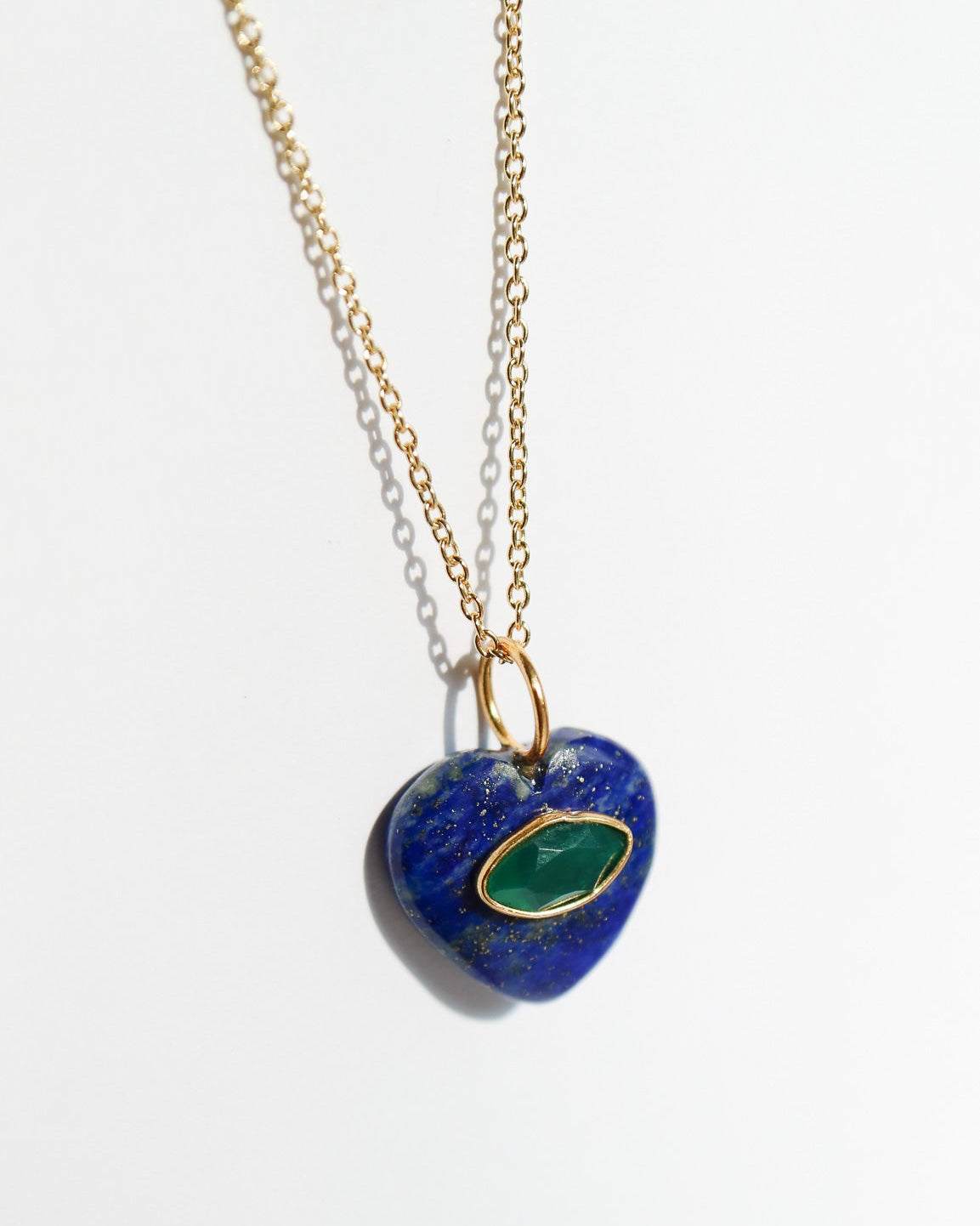Heart-shaped pendant with blue stone and gold chain on white background
