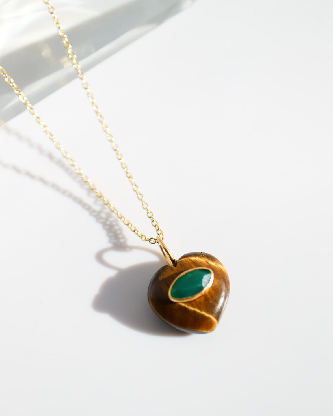 Necklace with a heart-shaped pendant featuring a green stone on a white background