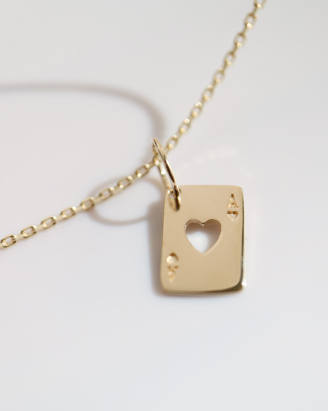 Gold necklace with a heart-shaped pendant on a light gray background