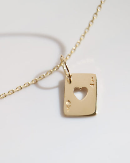 Gold necklace with a heart-shaped pendant on a light gray background