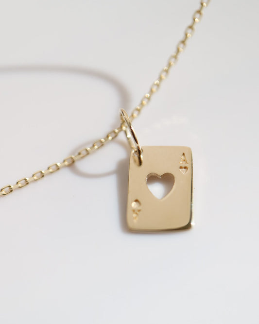 Gold necklace with a heart-shaped pendant on a light gray background