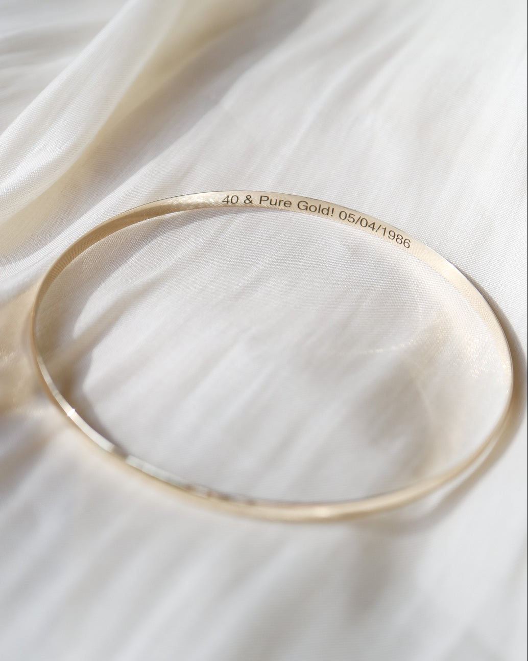 Gold bracelet on a white fabric background