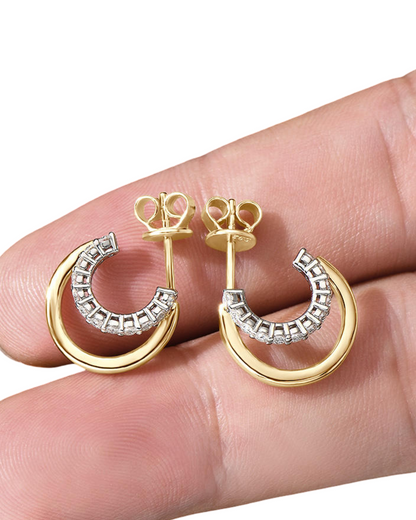 Gold and silver hoop earrings held between fingers on a white background