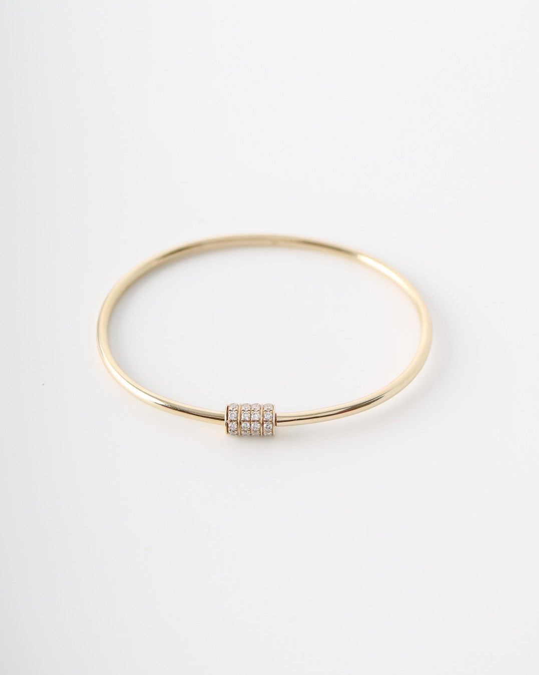 A thin gold bangle bracelet with a small rectangular bezel-set diamond accent, displayed on a clean white background.