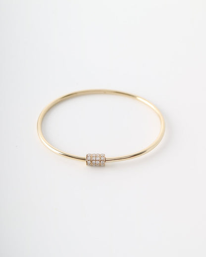A thin gold bangle bracelet with a small rectangular bezel-set diamond accent, displayed on a clean white background.