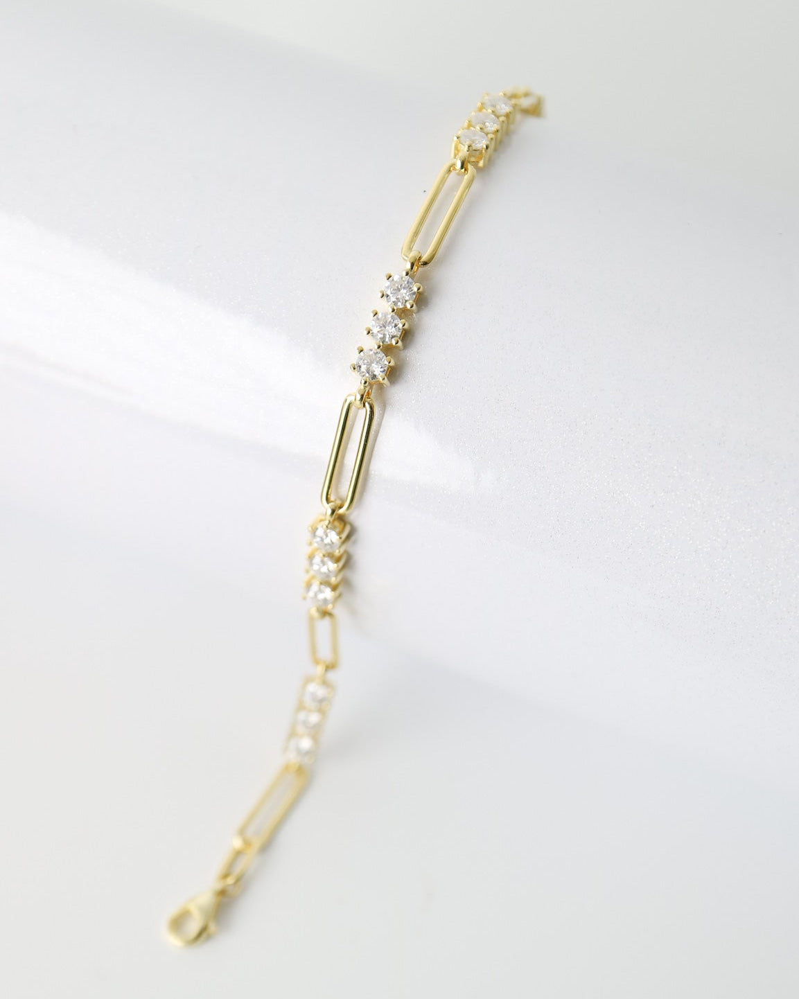A delicate gold paperclip chain bracelet with small clear crystal accents, displayed on a clean white surface.
