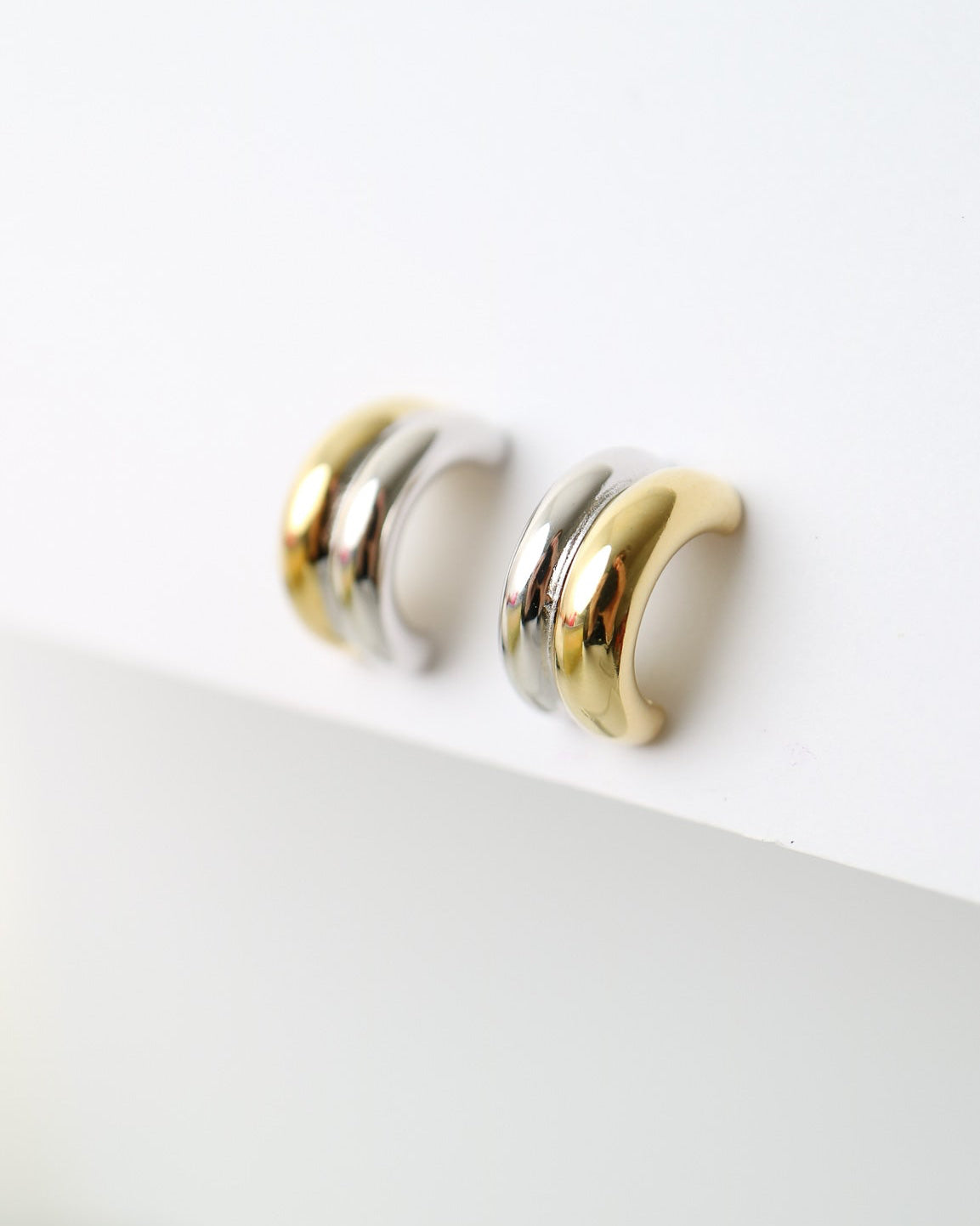 Interlude Hoops featuring a sculptural mixed-metal design with polished gold plated and sterling silver bands and butterfly back fastenings.