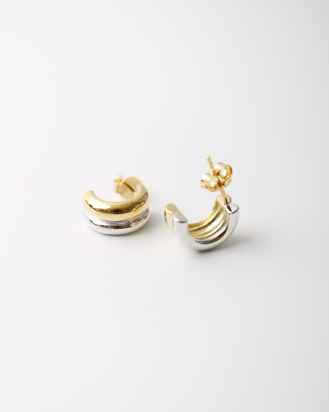 Interlude Hoops featuring a sculptural mixed-metal design with polished gold plated and sterling silver bands and butterfly back fastenings.