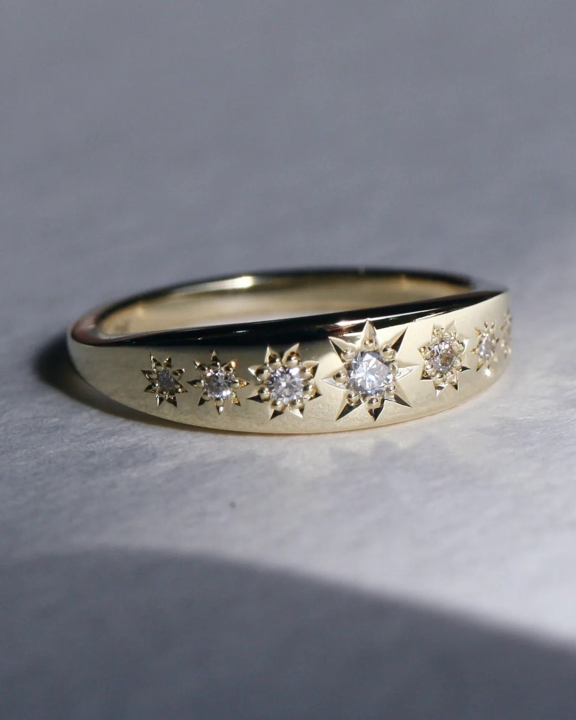 Gold ring with diamond accents on a gray background
