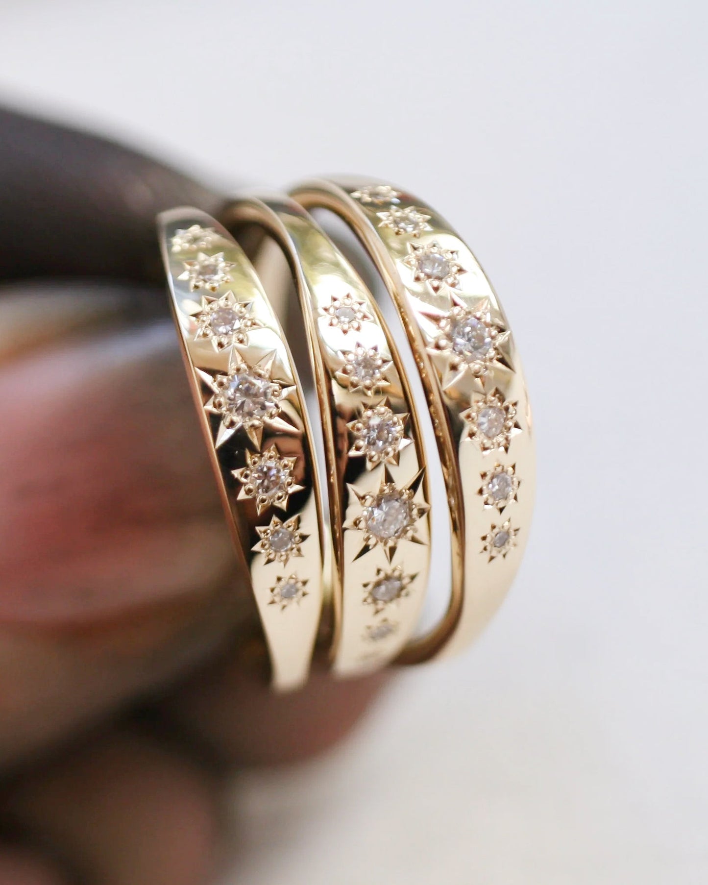 Three gold rings with diamond accents on a blurred background