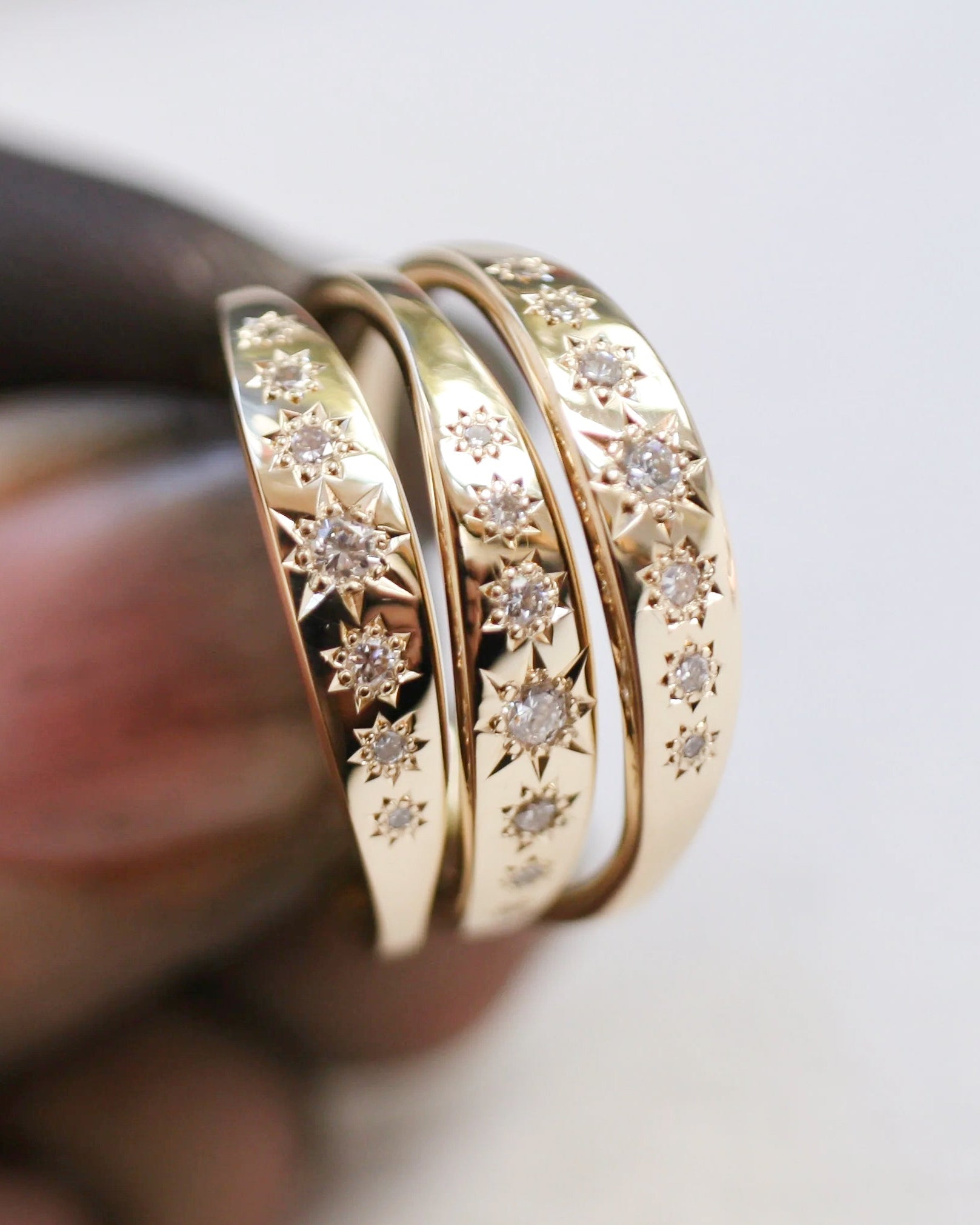 Three gold rings with diamond accents on a blurred background