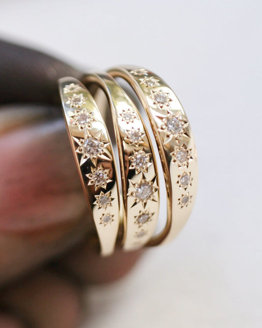 Three gold rings with diamond accents on a blurred background