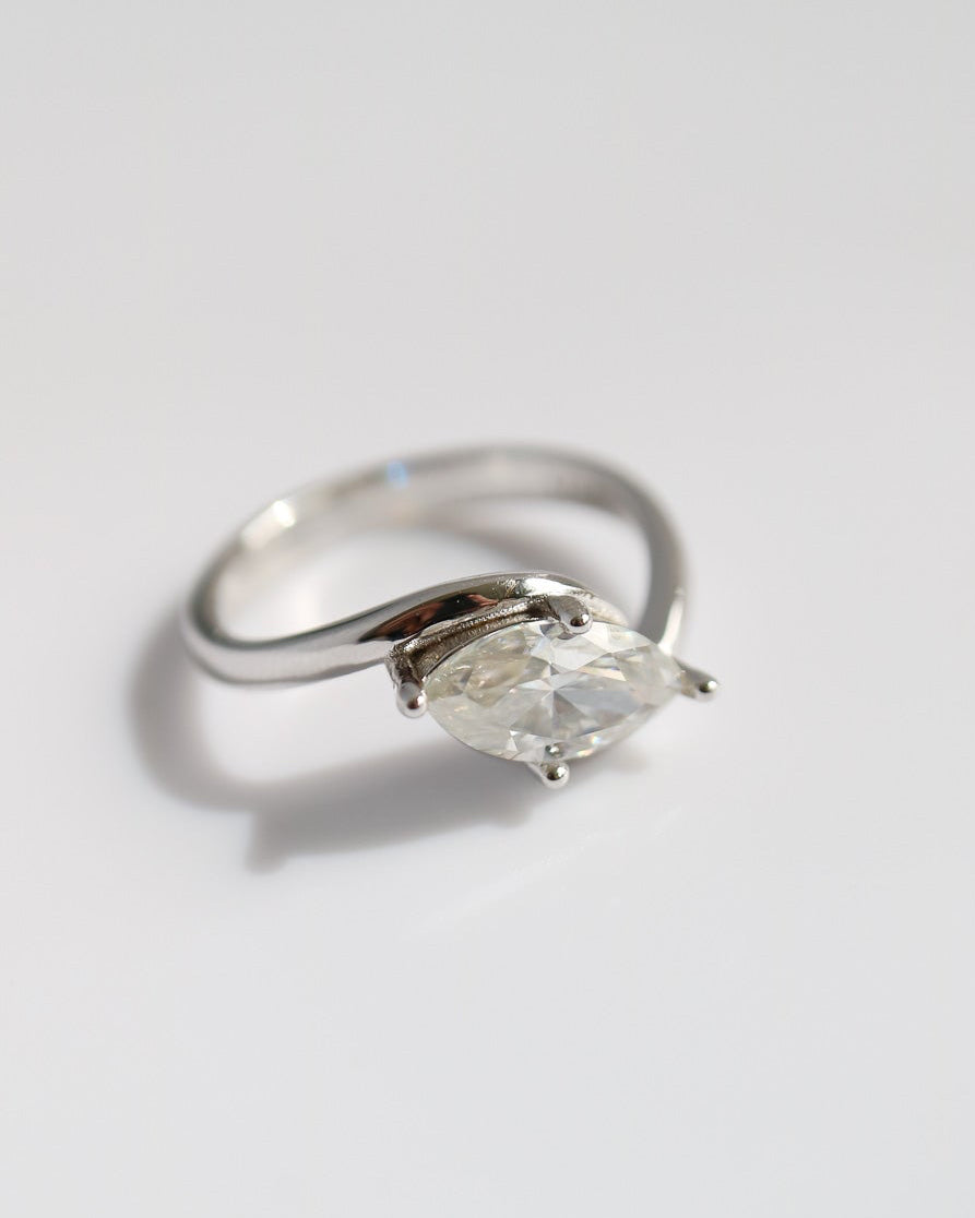 Silver ring with a marquise shaped diamond on a light gray background