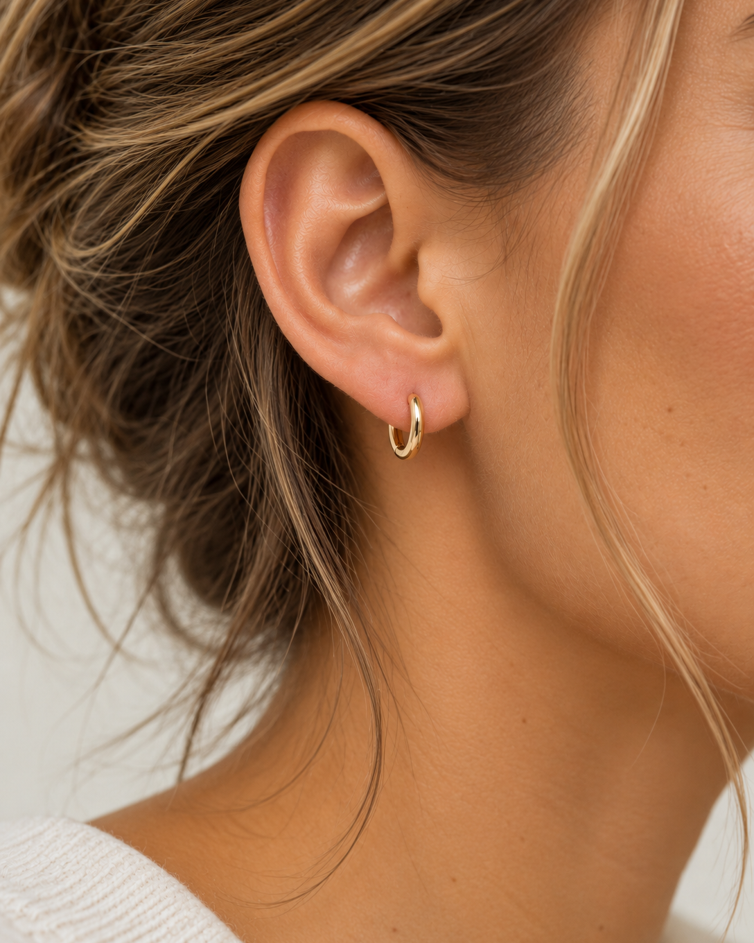 Pair of 9kt solid gold Rounded Huggie Earrings with a polished finish and classic circular design, shown worn on a woman's earlobe.
