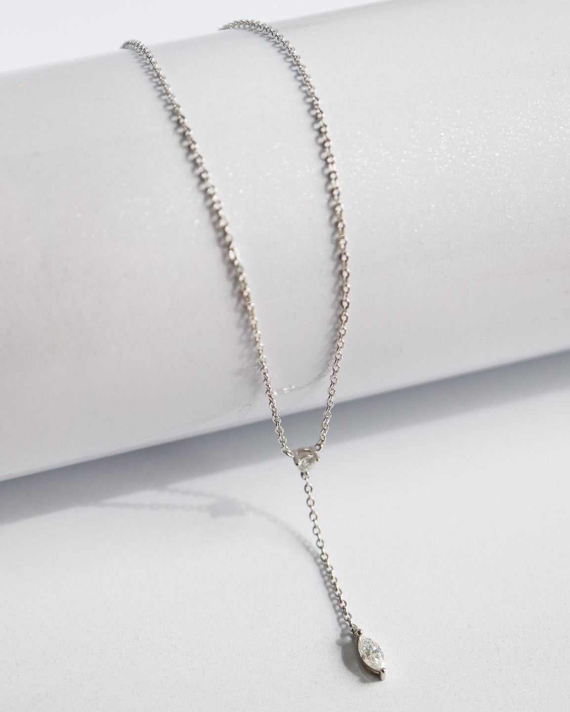 Silver necklace with a small pendant on a white surface