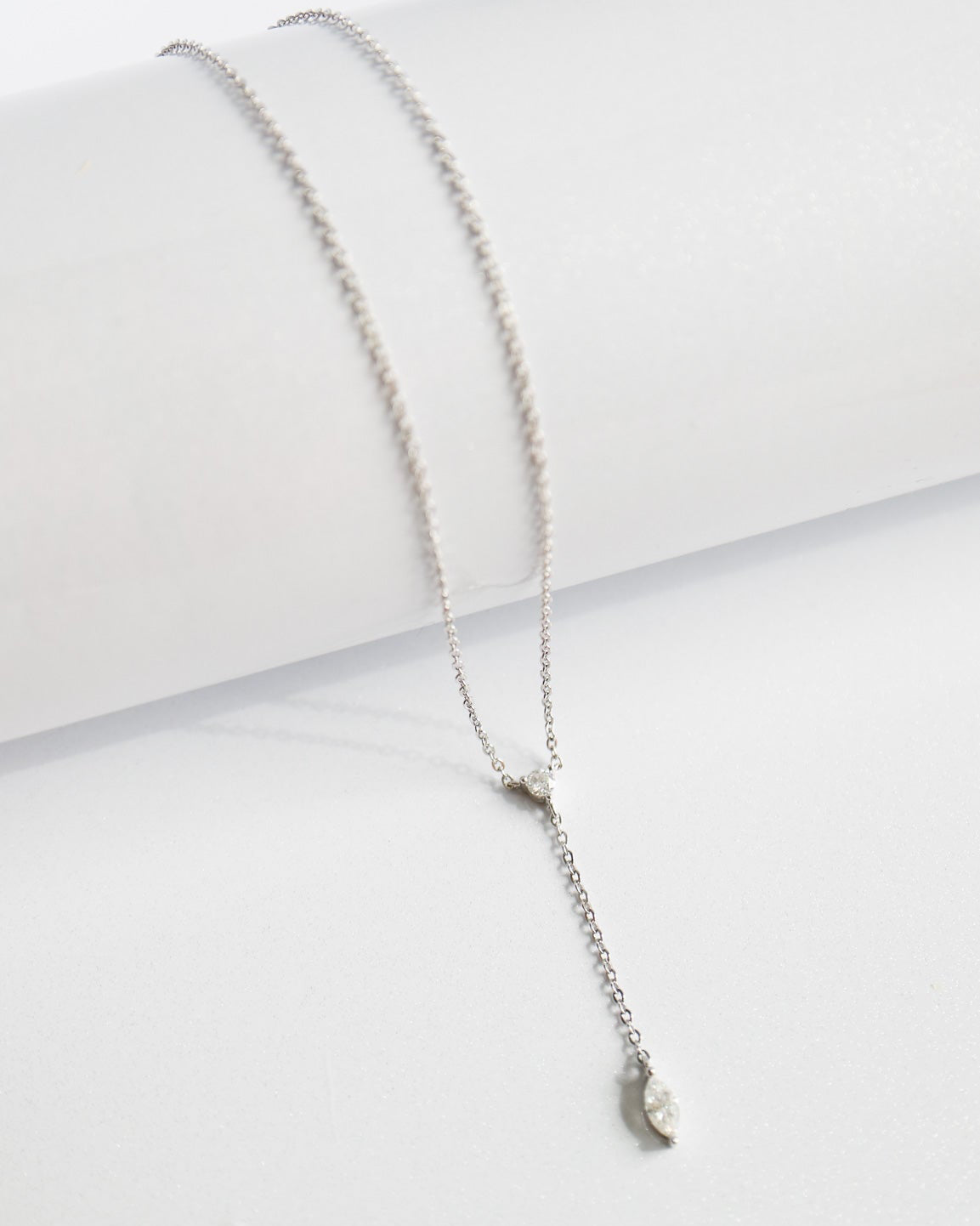 Silver necklace with a small pendant on a white surface
