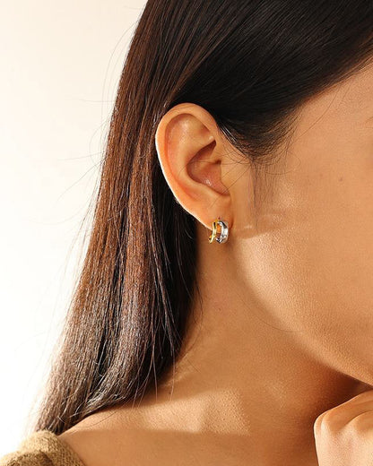 Close-up of a woman wearing a silver earring with a plain background