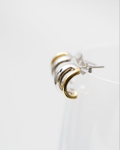 Silver and gold earring on a white background